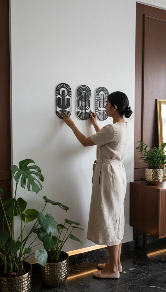 Woman installing wall art in a home setting with plants and furniture.