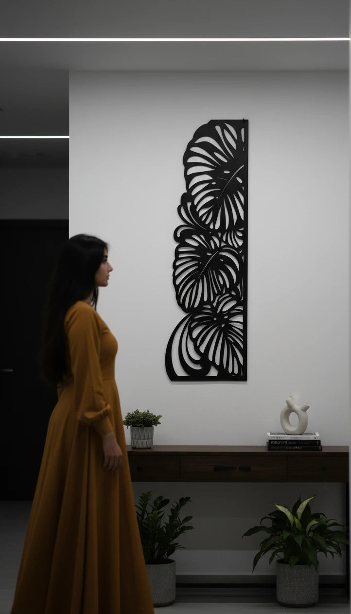 Woman in a yellow dress standing in a room with a decorative wall art piece.