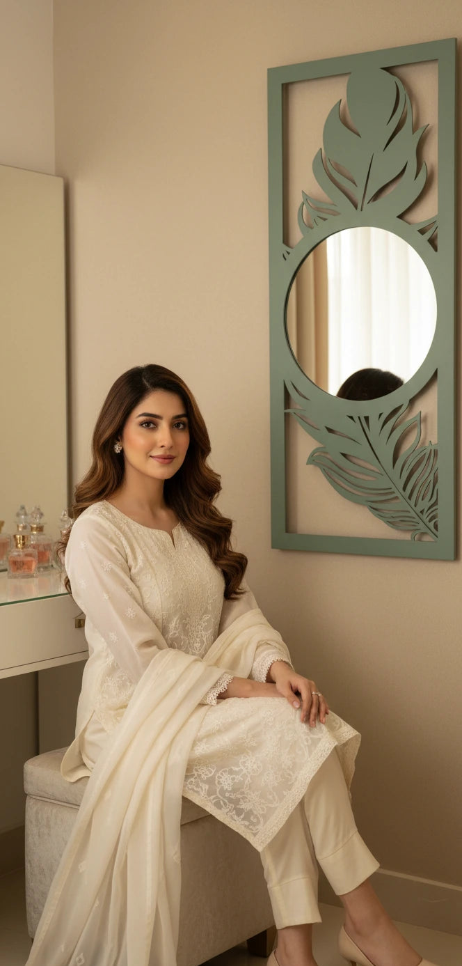 Woman in a white outfit sitting in front of a decorative mirror.