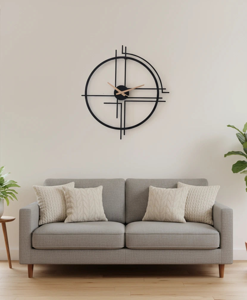 Gray sofa with decorative pillows in a room with a large wall clock.