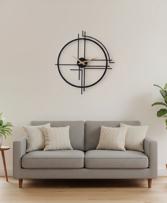 Gray sofa with decorative pillows in a room with a large wall clock.