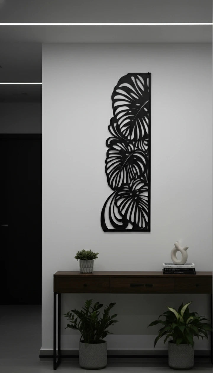 Decorative metal wall art with leaf design on a white wall above a console table.