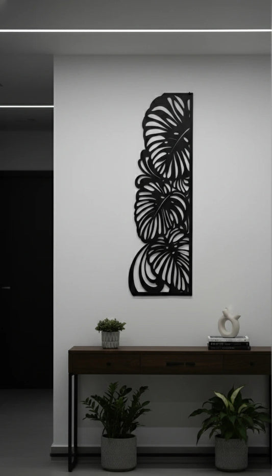 Decorative metal wall art with leaf design on a white wall above a console table.