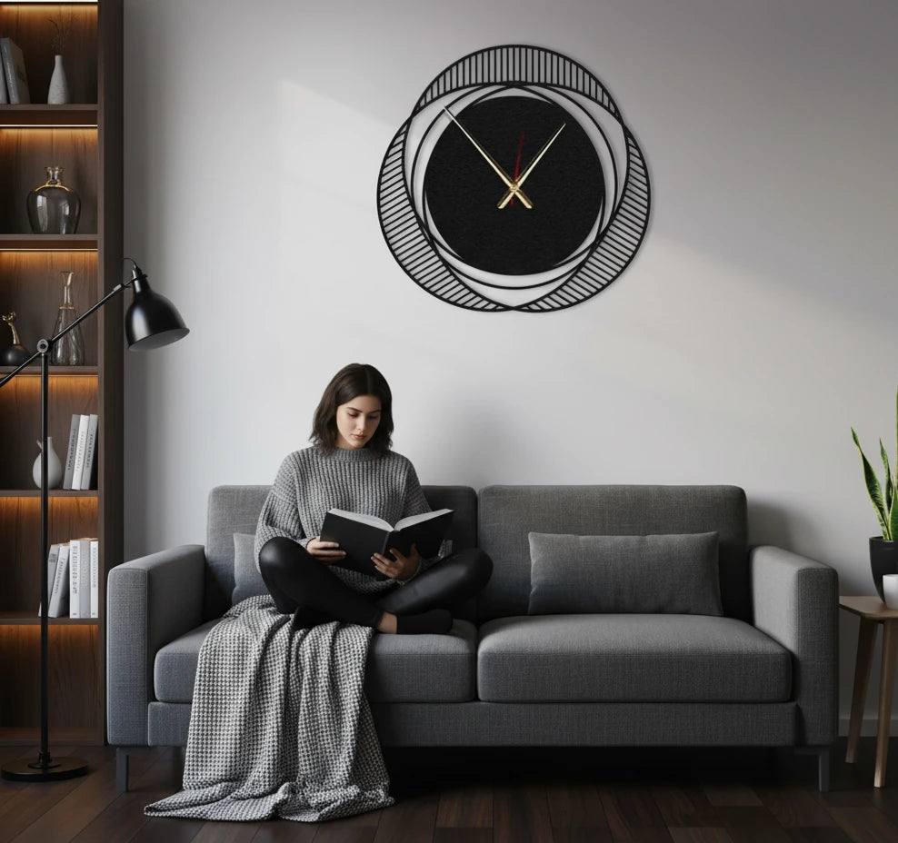 Woman reading a book on a gray sofa in a modern living room with a decorative wall clock.