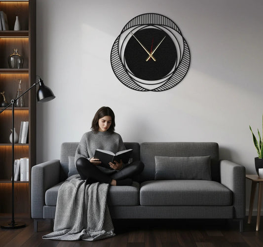 Woman reading a book on a gray sofa in a modern living room with a decorative wall clock.