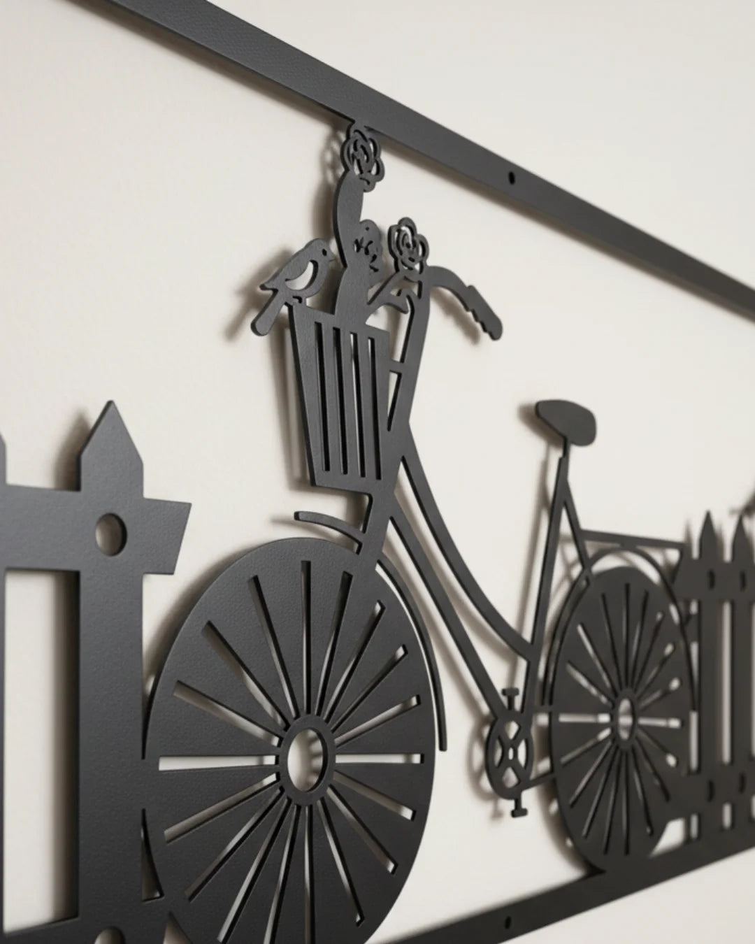 Decorative metal wall art of a bicycle with a basket and fence.